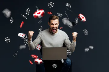 A man celebrating a winning moment on his laptop while gaming symbols float around him, capturing the excitement of CT44 games.