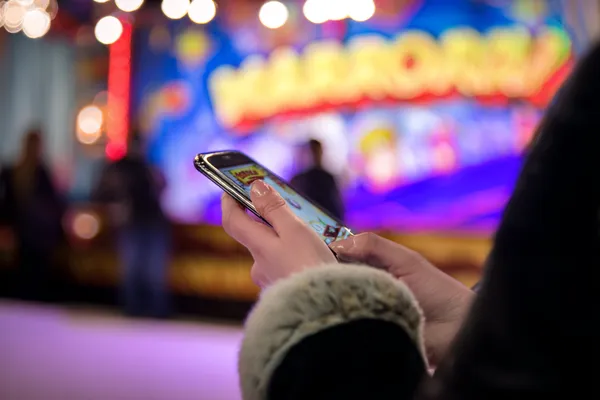 A player using their smartphone during a festive local event, representing CT44’s fully mobile-friendly casino.